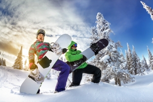 A couple being playful holding snowboard as a guitar in the snow