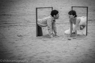 a couple looking at each other romantically in the beach with woman wearing a wedding dress for pre-wedding photo
