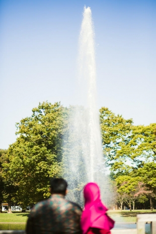 Vacation photo of a couple sitting in front of a big fountain in Yoyogi park, Tokyo
