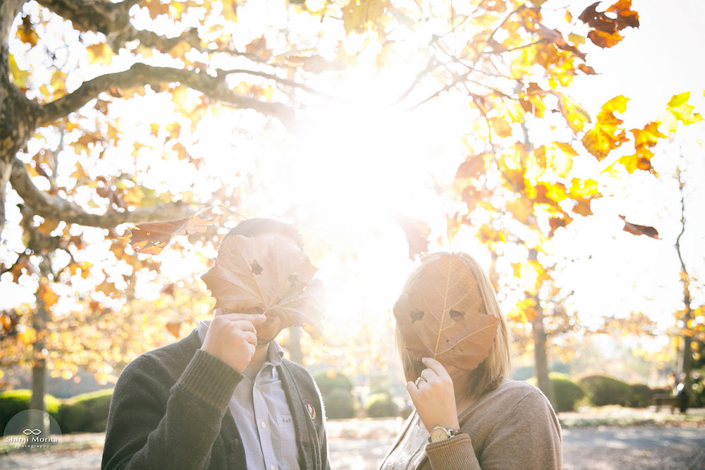 A couple being playful with leaves in Autumn in Shinjuku Gyoen park