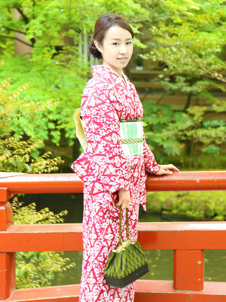 A woman posing at the bridge in Kyoto wearing a red kimono