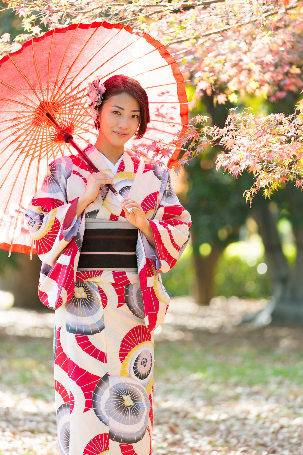 A woman holding a Japanese umbrella wearing a modern patterned kimono