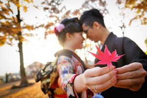 A couple holding a red maple leaf during their pre-wedding photo