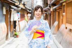 A woman holding sensu fan in her hand wearing kimono