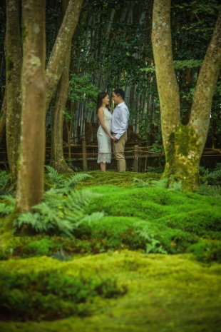 Vacation photo of a couple looking at each other surrounded by beautiful moss garden in Arashiyama, Kyoto