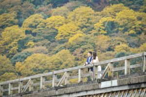 Vacation photo of a couple looking at Hozu river from Togetsukyo bridge in Arashiyama, Kyoto